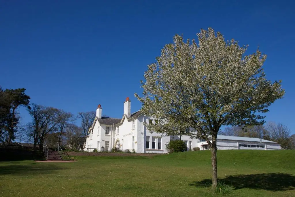 a white house with a tree in front of it at Fife Lodge Hotel in Banff