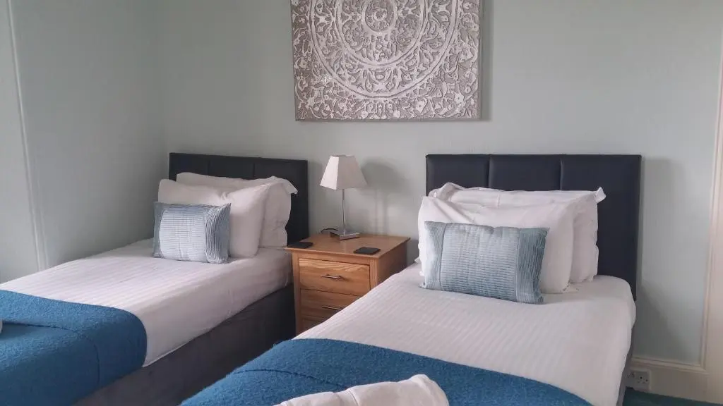 a bedroom with two beds and a picture on the wall at Kinnaird Country House with Hot Tub in Pitlochry