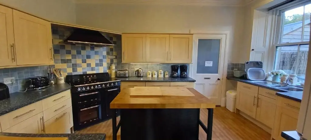 a kitchen with wooden cabinets and a black stove at Kinnaird Country House with Hot Tub in Pitlochry