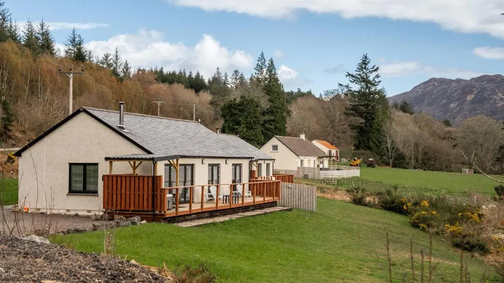 a white house with a deck on a yard at Shoreland Lodges - Cherry Lodge in Fort Augustus
