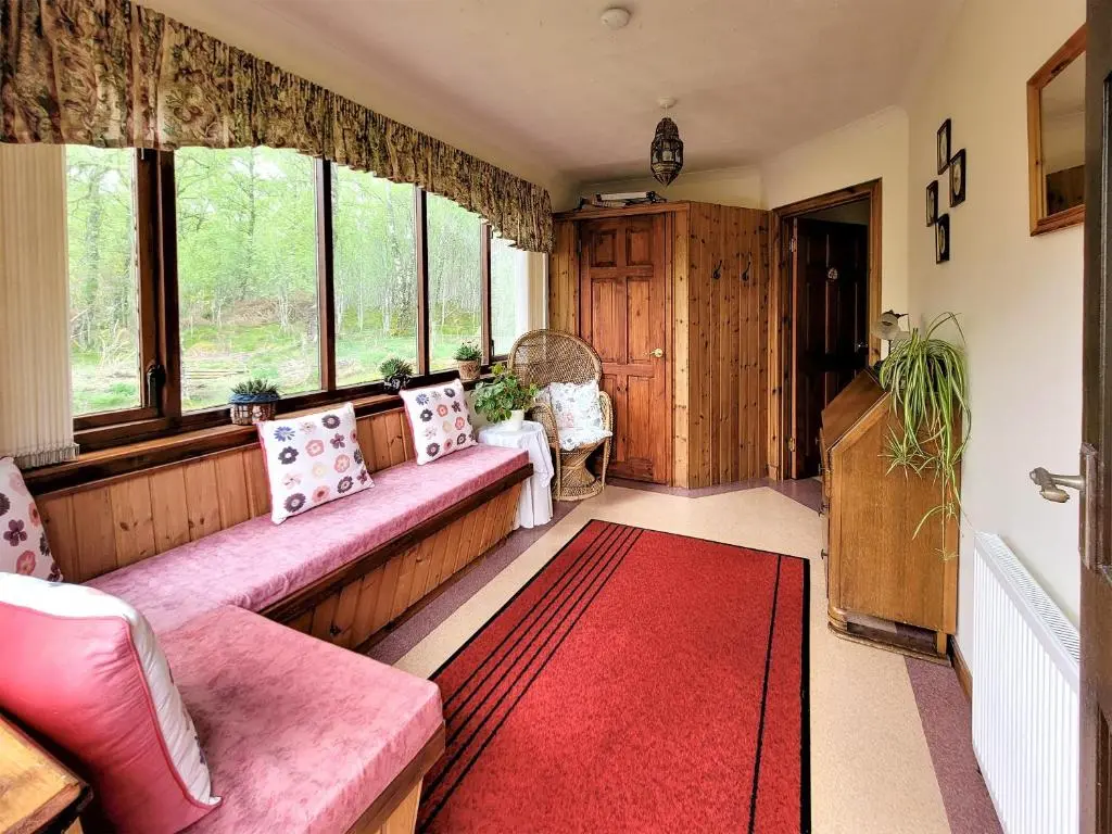 a living room with a couch and a red rug at The Birches in Ardclach