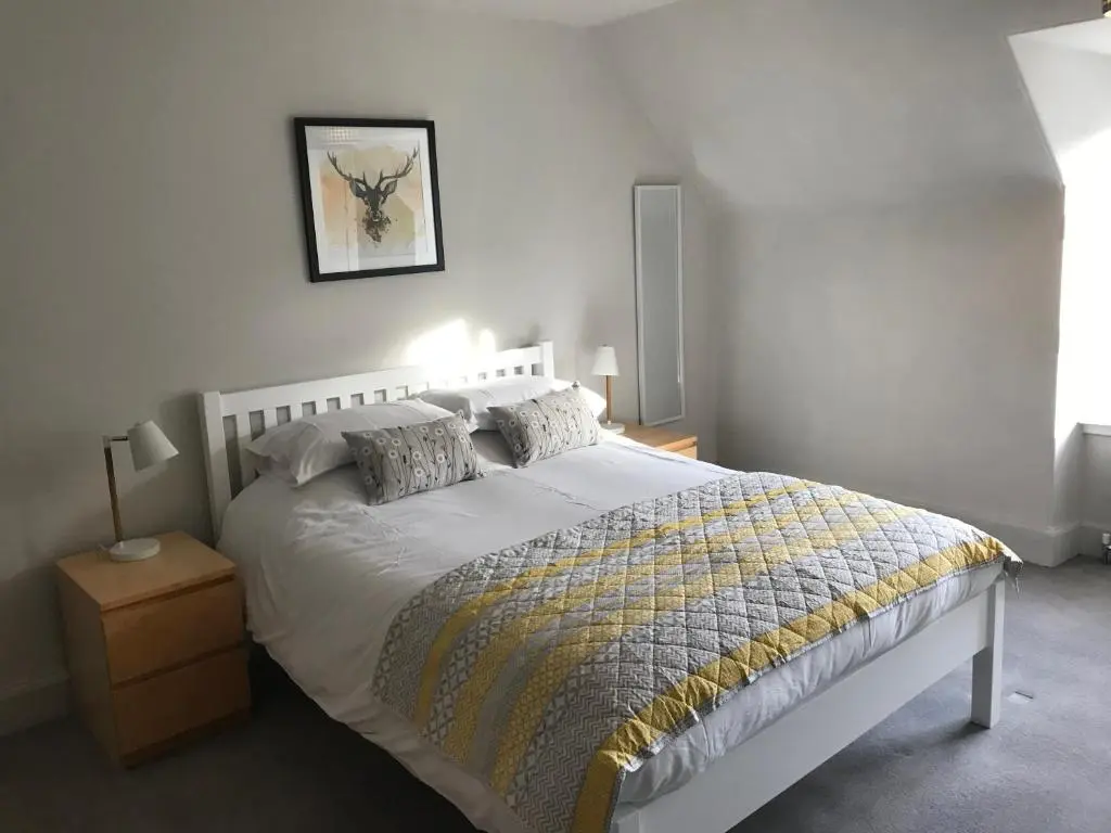 a bedroom with a white bed with a yellow and gray blanket at Fantastic central location in Inverness