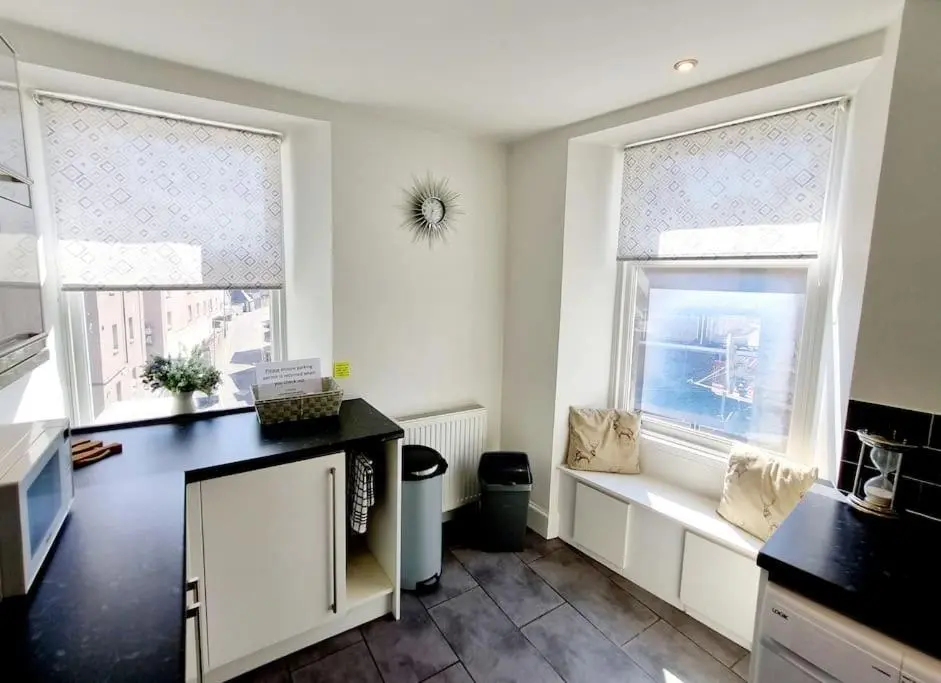 a kitchen with two windows and a black counter top at Highland Historical Home in Inverness City Centre in Inverness