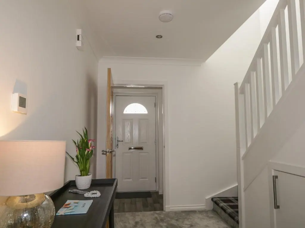 a hallway with a door and a table with a lamp at 15 Waters Edge in Banff