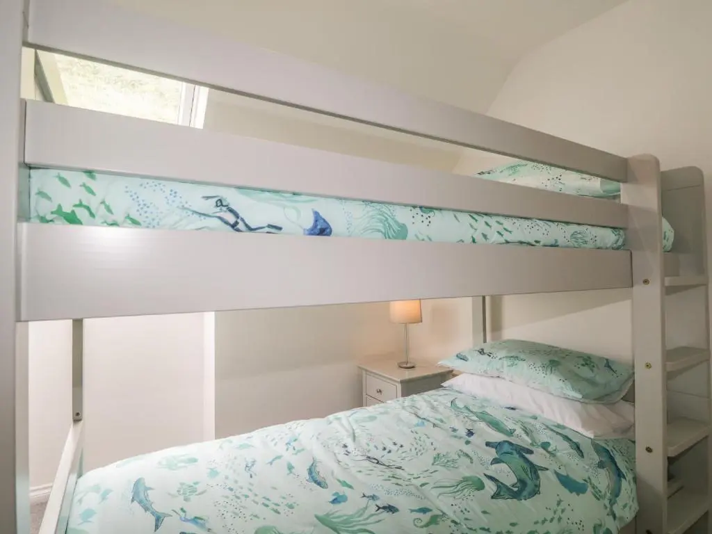 a bedroom with a bunk bed with blue and green sheets at 15 Waters Edge in Banff