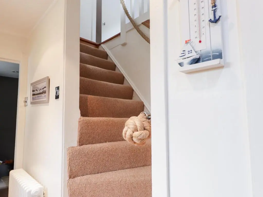 a hallway with stairs with a teddy bear on the floor at 61 Seatown in Buckie