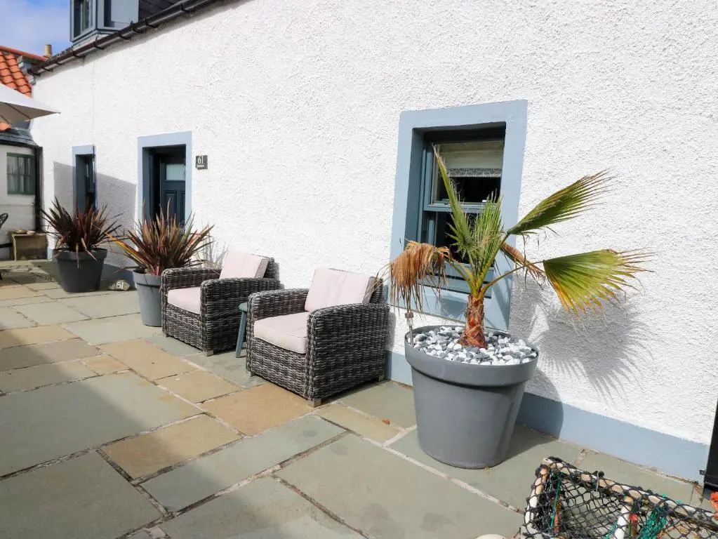a patio with chairs and palm trees in front of a building at 61 Seatown in Buckie