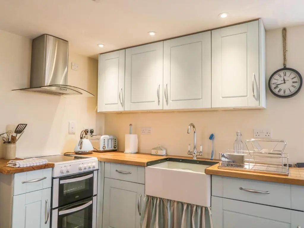 a kitchen with white cabinets and a sink and a clock at 11 Village in Banff
