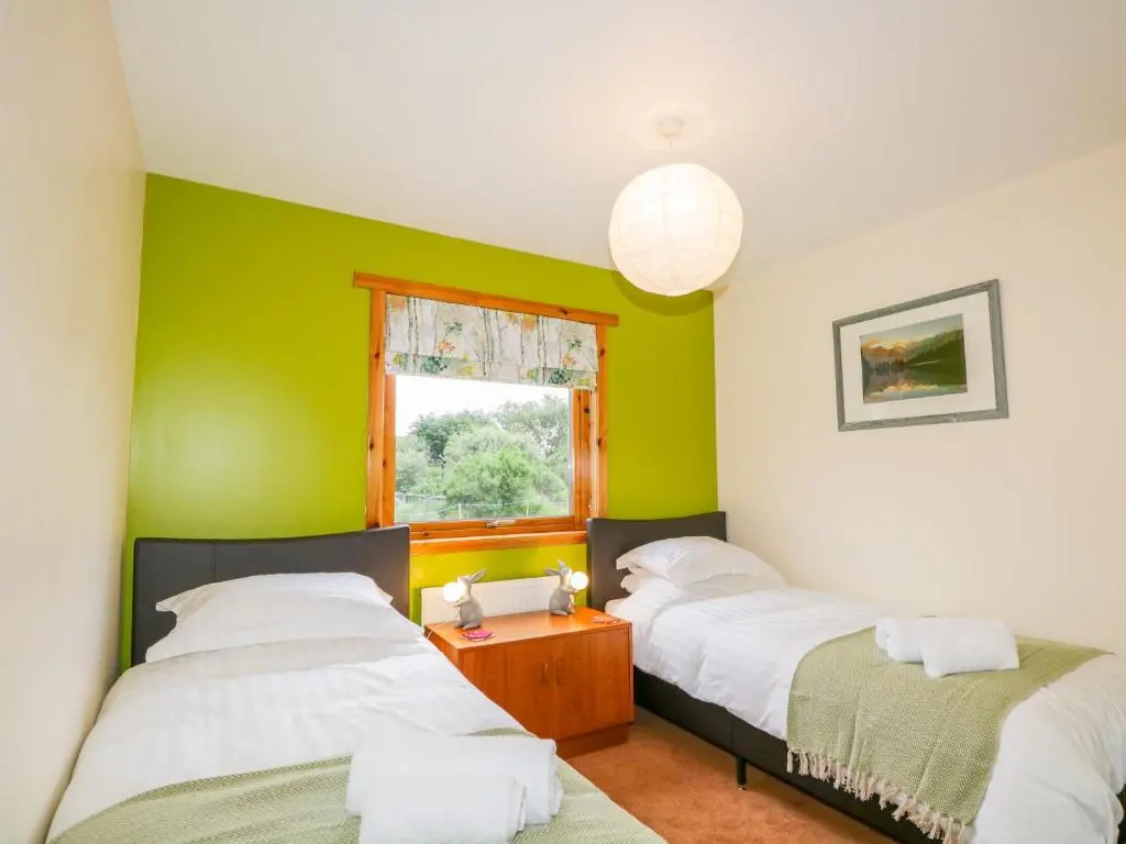 two beds in a room with green walls at Ptarmigan in Carrbridge