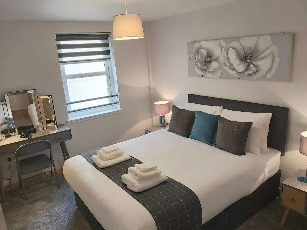 a bedroom with a large bed with two towels on it at Inverness City Centre Apartment with Elevator and Google Chromecast in Inverness