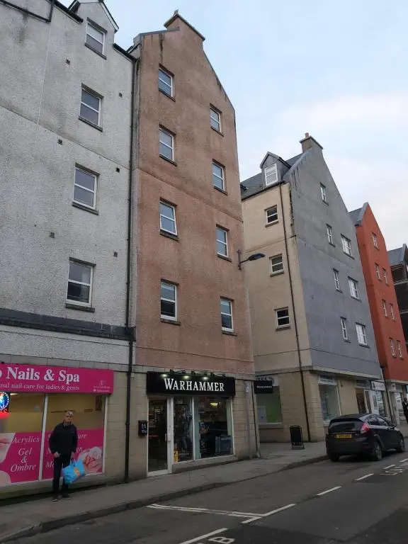 a man walking down a street in front of a building at Inverness City Centre Apartment with Elevator and Google Chromecast in Inverness