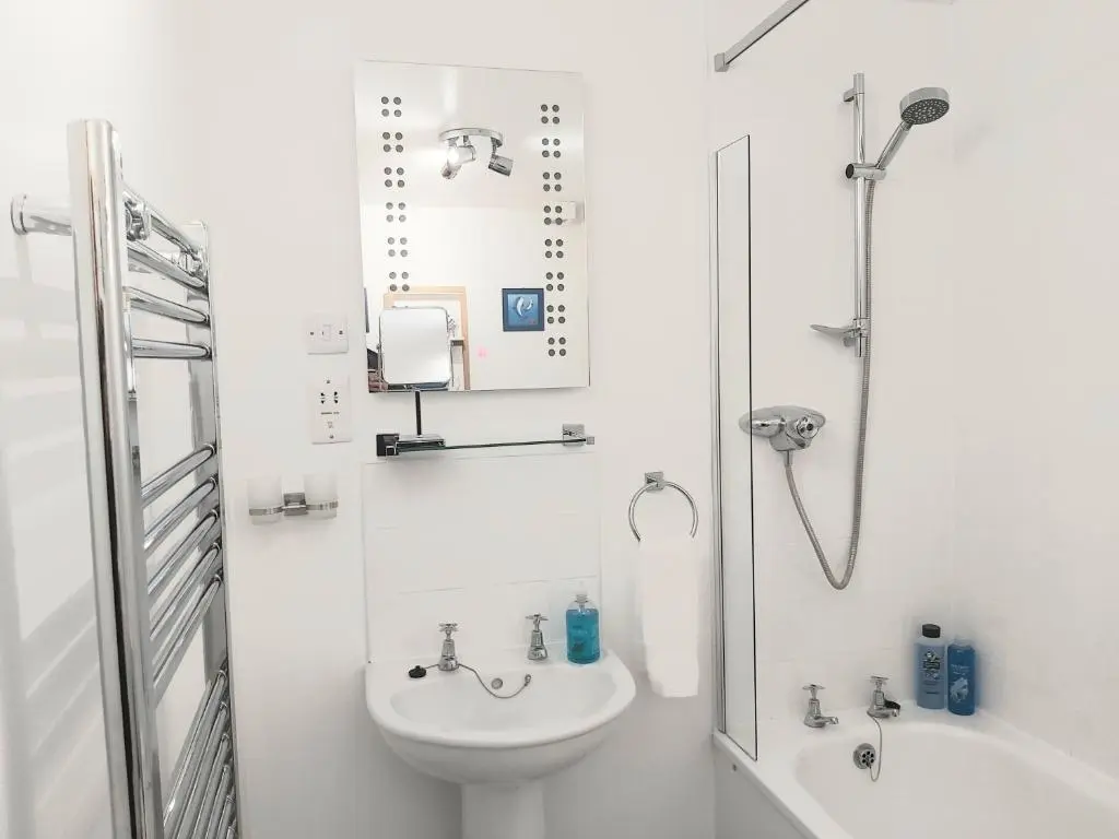 a white bathroom with a sink and a shower at Inverness City Centre Apartment with Elevator and Google Chromecast in Inverness