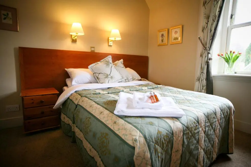 a hotel room with a bed with two towels on it at The Tomich Hotel in Tomich
