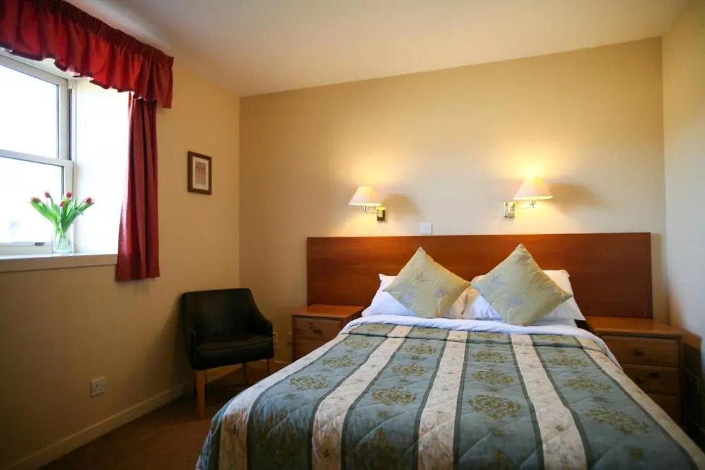 a hotel room with a bed and a chair at The Tomich Hotel in Tomich