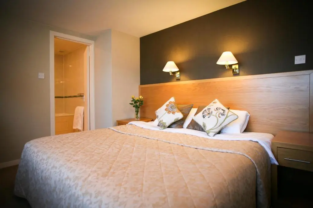 a hotel room with a large bed and a bathroom at The Tomich Hotel in Tomich