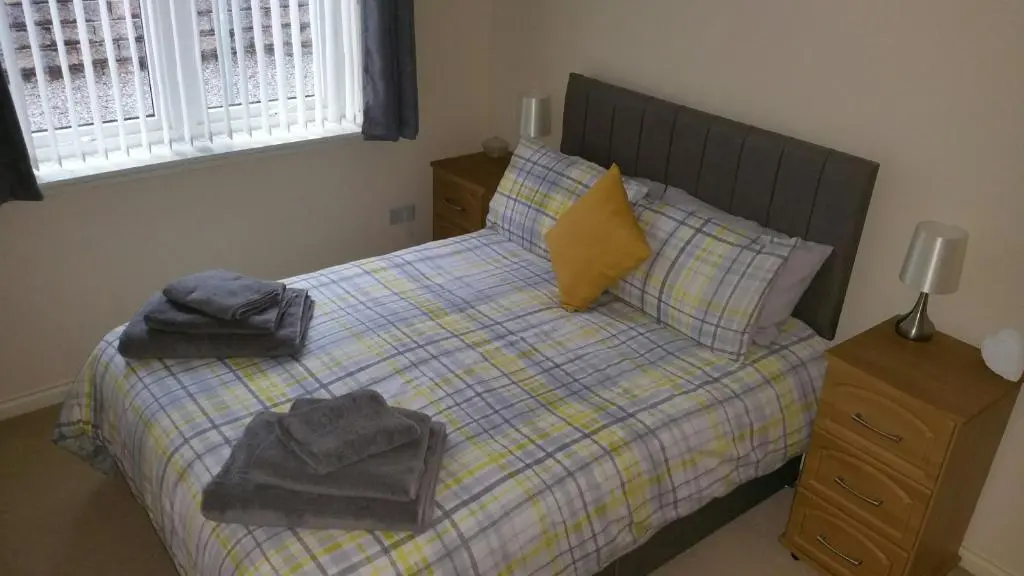a bedroom with a bed with towels on it at Lerwick Garden Apartment in Inverness