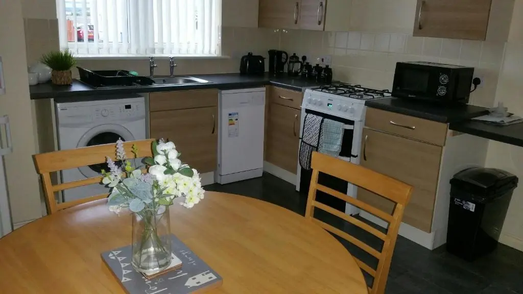 a kitchen with a table with a vase of flowers on it at Lerwick Garden Apartment in Inverness