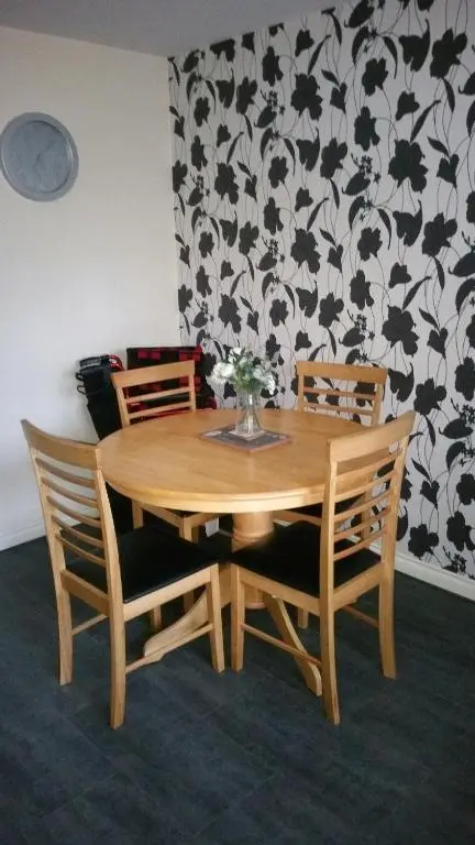 a wooden table with two chairs and a vase with flowers at Lerwick Garden Apartment in Inverness