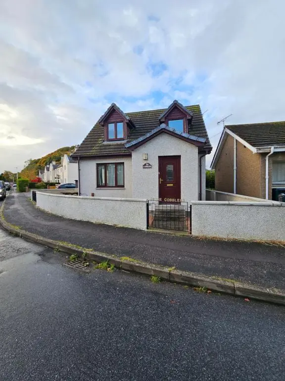a white house on the side of a street at The Cobblers in Inverness