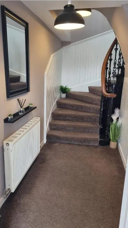 a hallway with stairs with a mirror and plants at City Centre Flat, Harbour View in Inverness