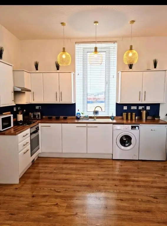 a kitchen with white cabinets and a washing machine at City Centre Flat, Harbour View in Inverness