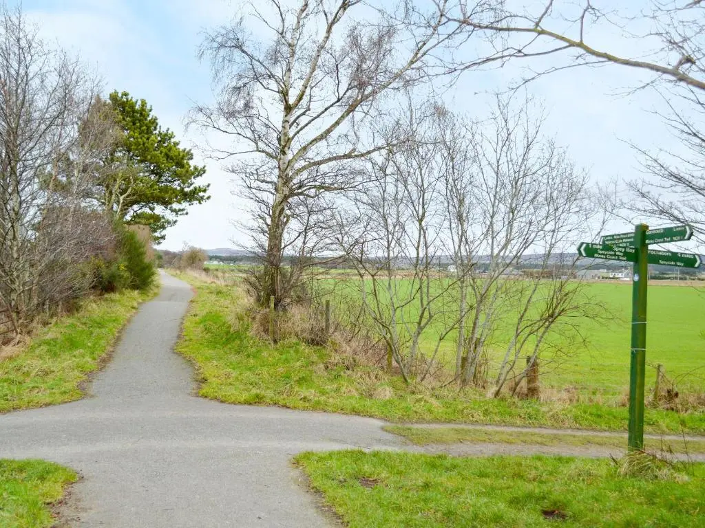 a dirt road with a street sign next to a field at March Brown in Garmouth