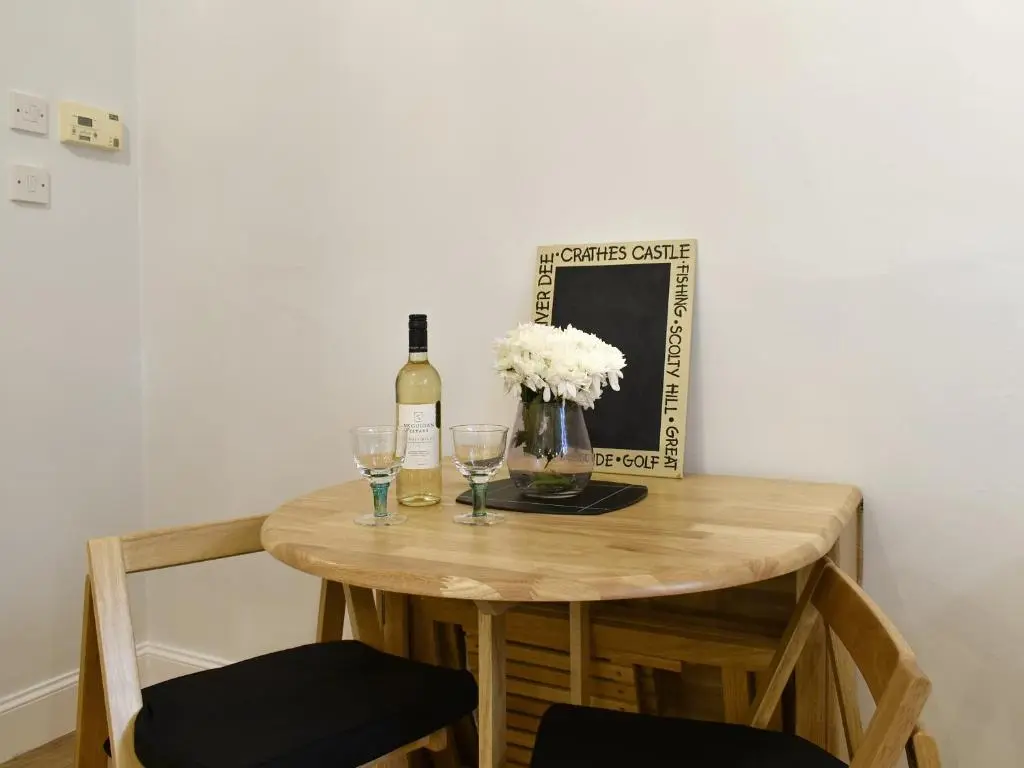 a wooden table with a bottle of wine and glasses at West Lodge in Banchory