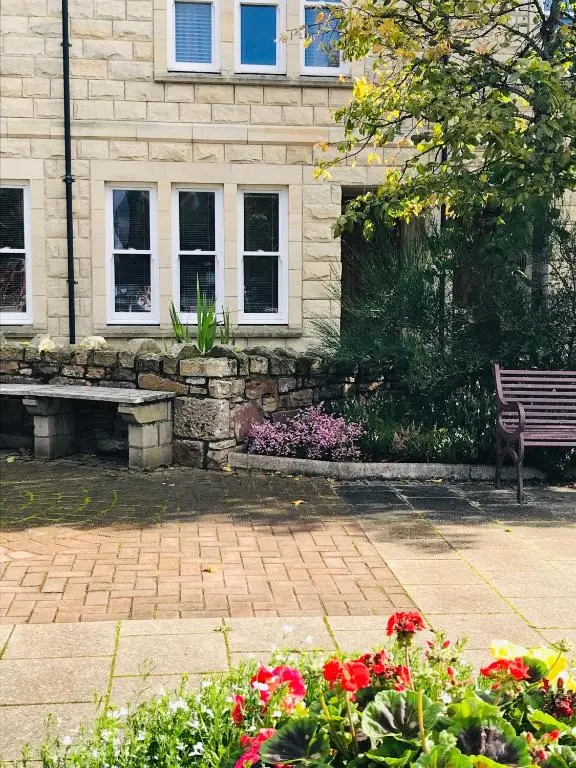 a park bench in front of a building with flowers at 3 Argyle Place in Dornoch