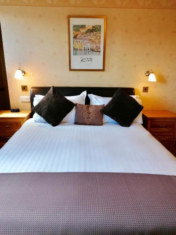 a bedroom with a large white bed with black pillows at Lyndon Guest House in Inverness