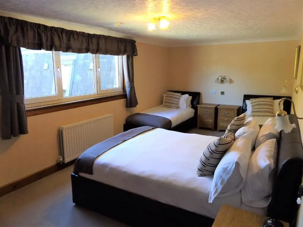a hotel room with two beds and a window at Lyndon Guest House in Inverness