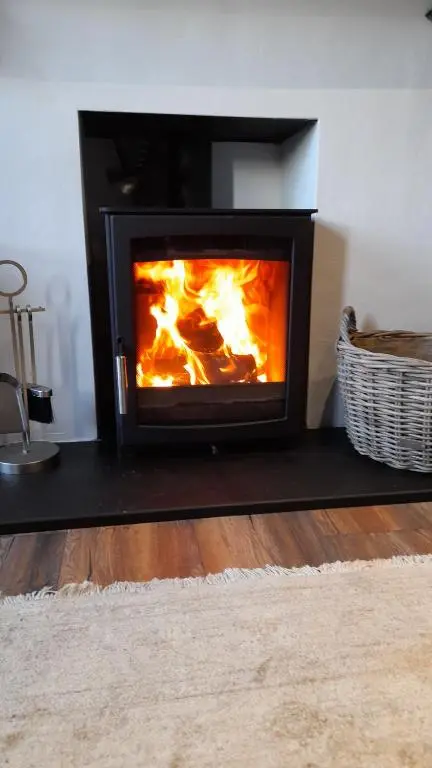 a fireplace in a living room with flames in it at The Dookit - Aviemore Town House in Aviemore