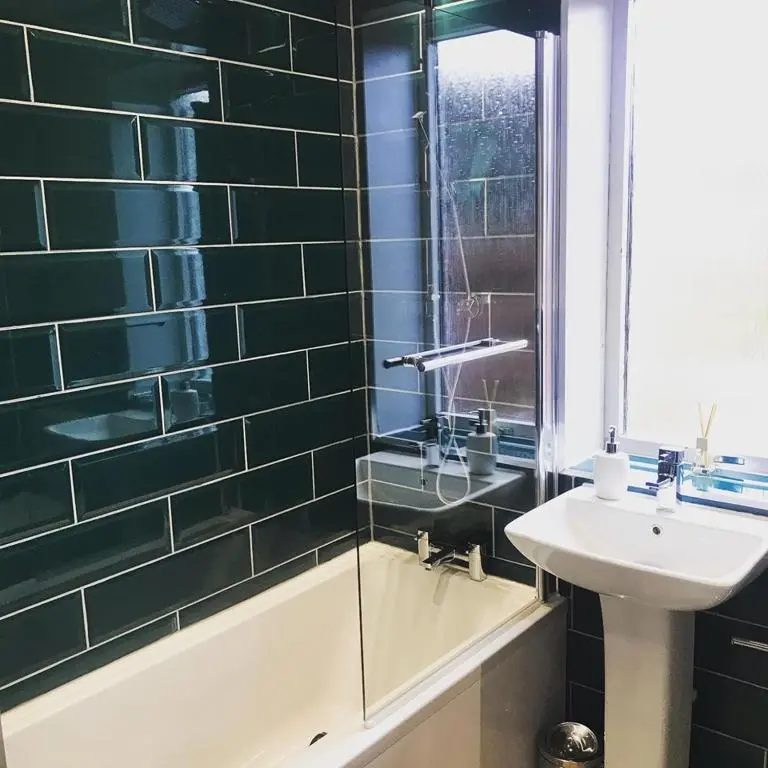 a bathroom with a bath tub and a sink and a window at The Dookit - Aviemore Town House in Aviemore