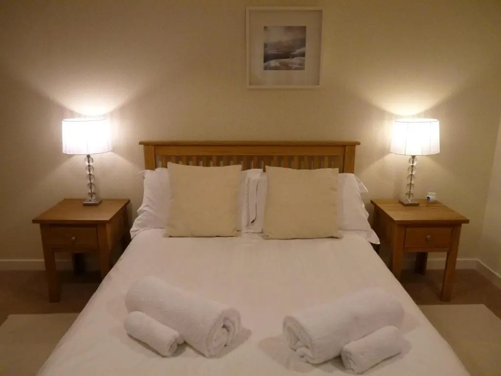 a bedroom with a large white bed with two lamps at Loch Ness Abbey Cottages in Fort Augustus