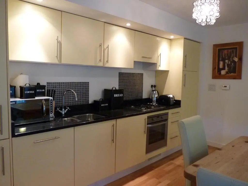 a kitchen with white cabinets and a dining table at Loch Ness Abbey Cottages in Fort Augustus
