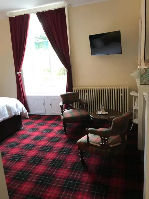 a hotel room with a bed and a table and chairs at Tullich House in Keith