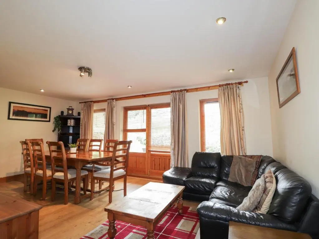 a living room with a black leather couch and a table at An Torr in Newtonmore