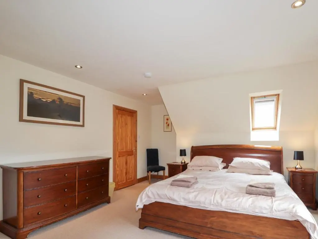 a bedroom with a large bed and a wooden dresser at An Torr in Newtonmore