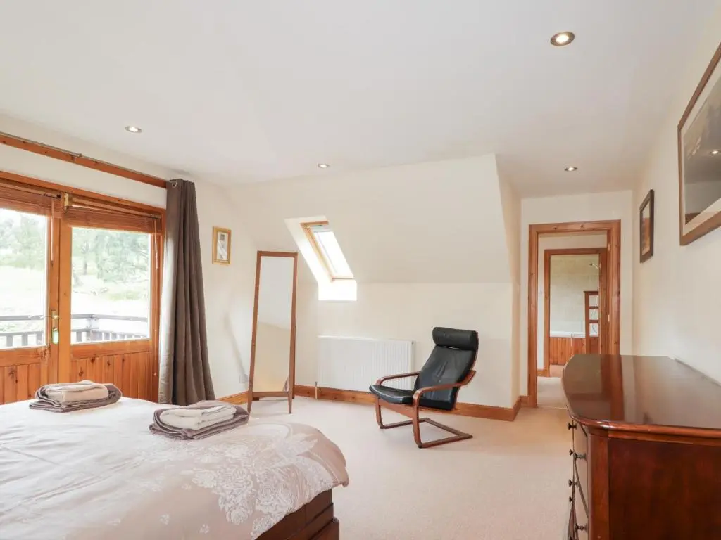 a bedroom with a bed and a chair and a window at An Torr in Newtonmore
