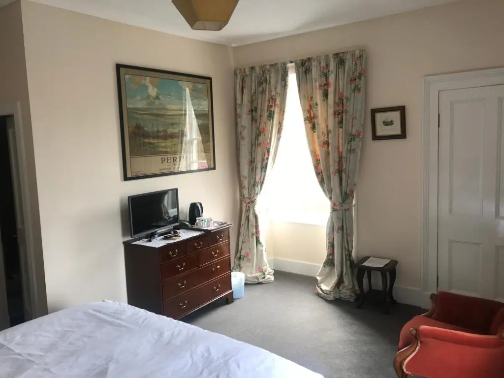 a bedroom with a bed and a television and a window at Kilmorie House in Elgin