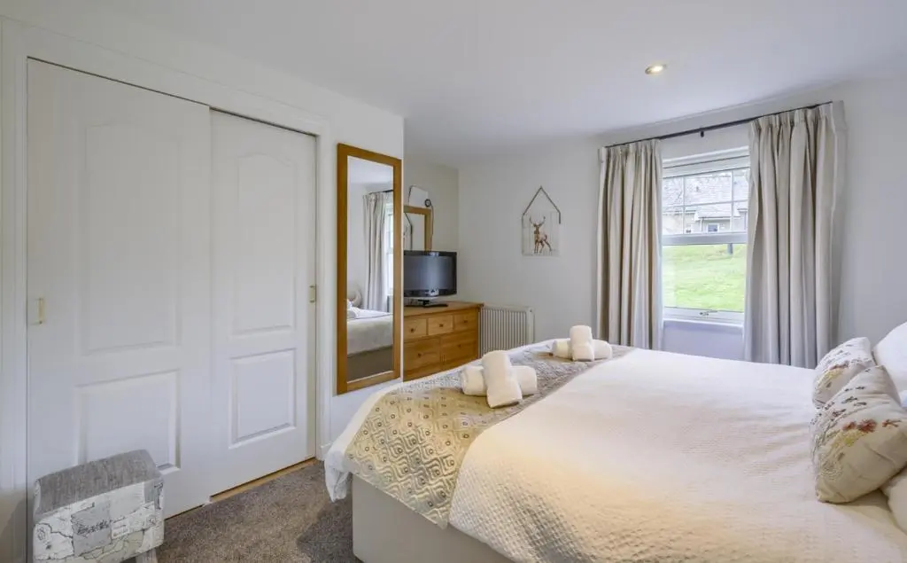 a bedroom with a large bed and a mirror at Apartment 20 Inchmarlo in Banchory