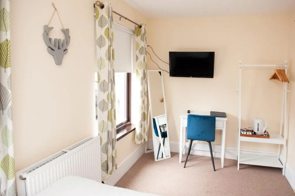 a room with a bed and a chair and a television at Alban and Abbey House in Inverness