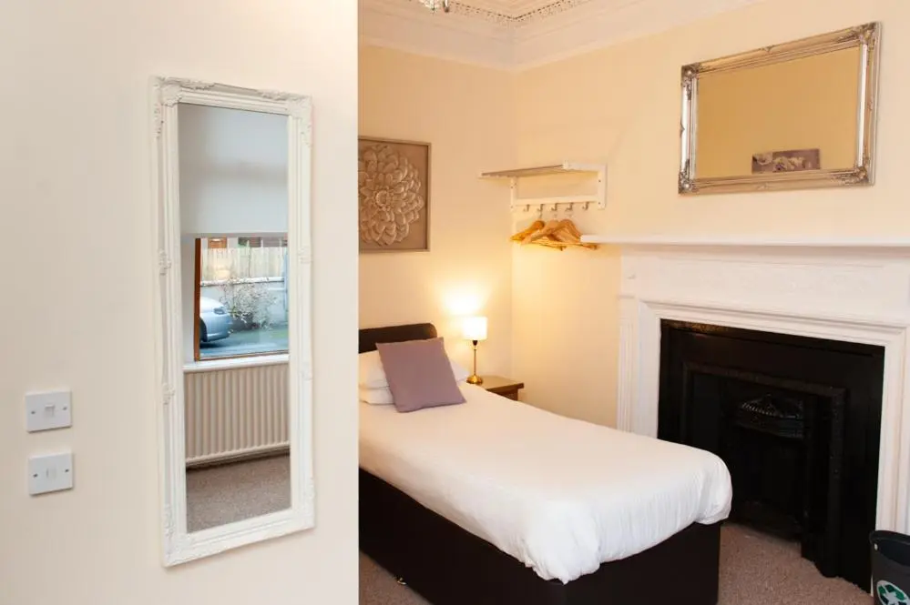 a bedroom with a white bed and a fireplace at Alban and Abbey House in Inverness