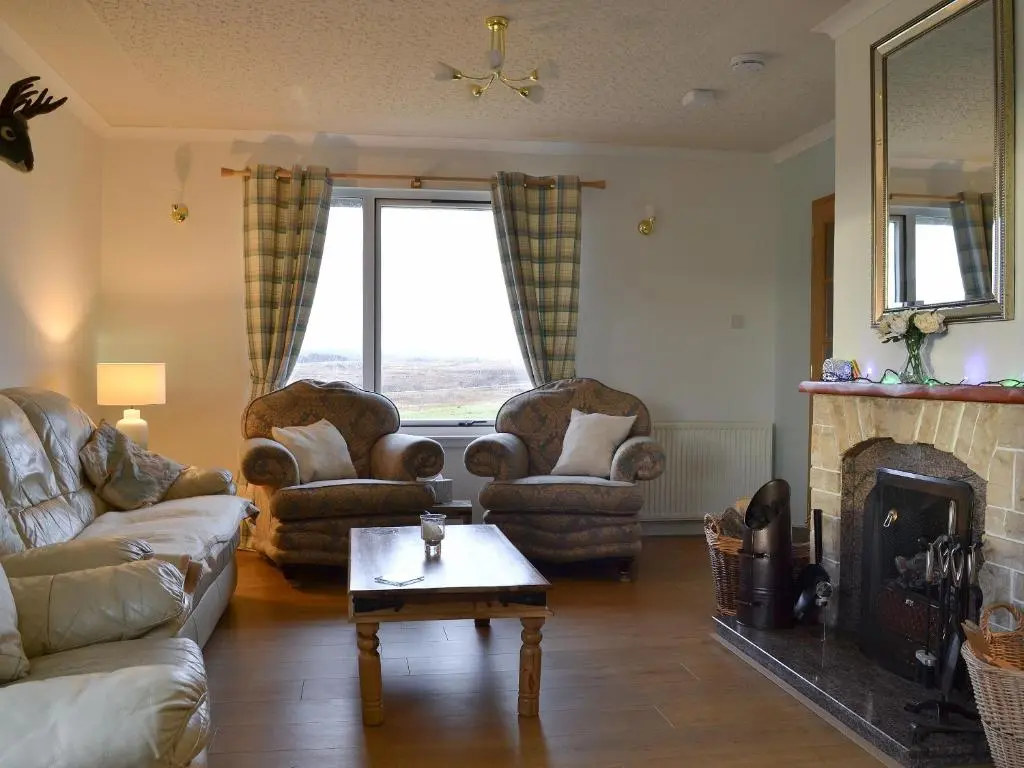 a living room with couches chairs and a fireplace at Fair View in Lairg
