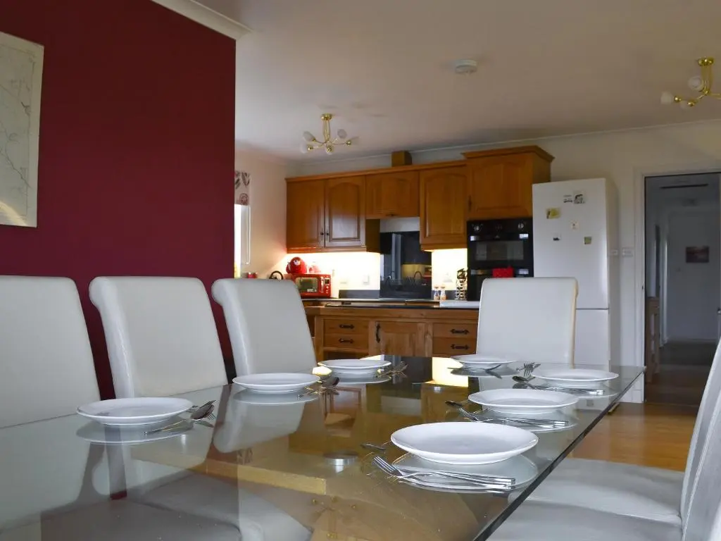 a kitchen with a glass table and white chairs at Fair View in Lairg