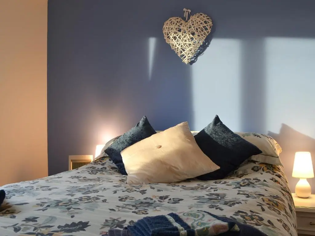 a bedroom with a bed with pillows and a heart on the wall at Fair View in Lairg