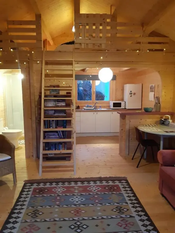 a living room with a table and a kitchen at Springbank Cabin in Insch