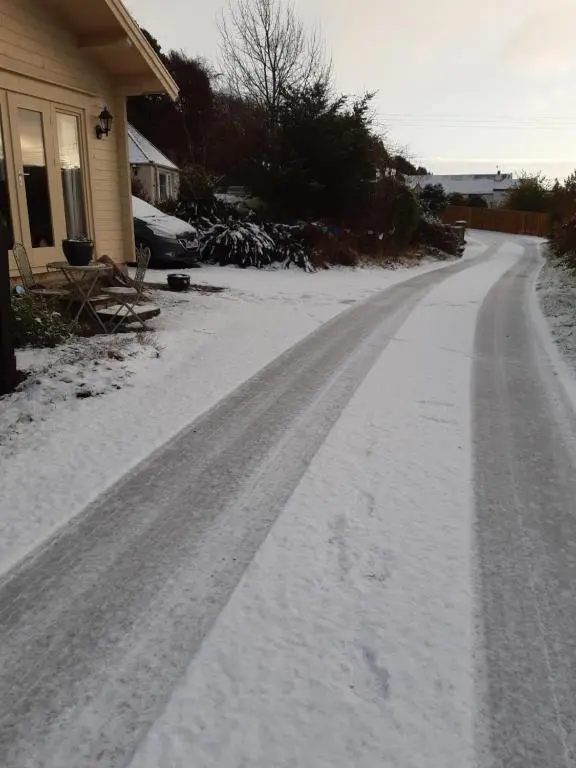 a driveway covered in snow next to a house at Springbank Cabin in Insch
