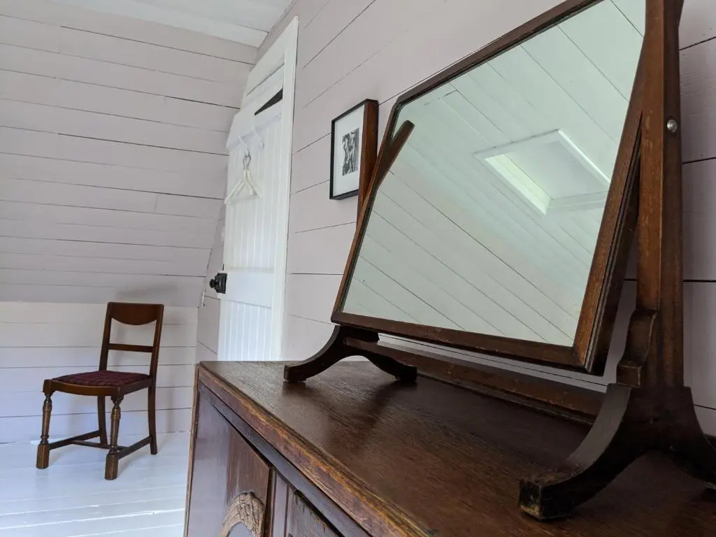 a mirror on a dresser in a room with a chair at Stable Cottage, CrannachCottages in Garve