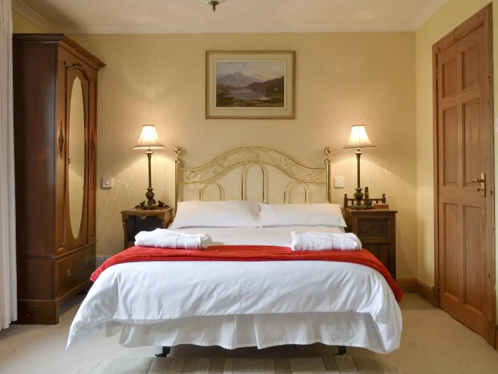 a bedroom with a large bed with two towels on it at Rowan Cottage in Aviemore
