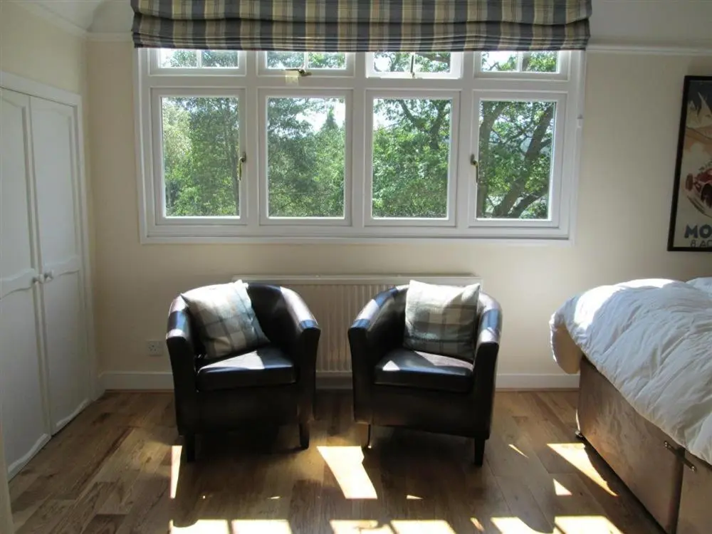 two chairs in a bedroom with a bed and windows at Shieling Beag in Banchory